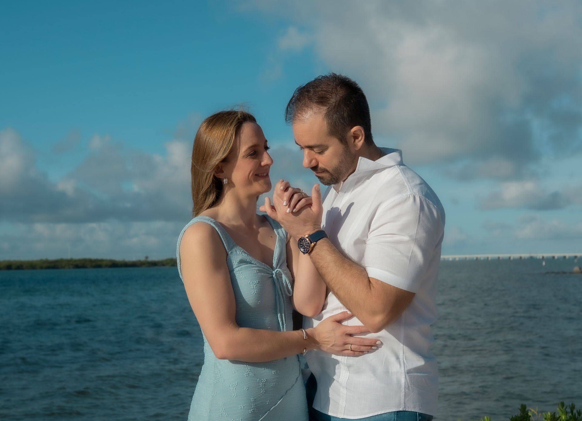 Ingrid and Miguel embracing by the water at sunset